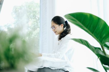 Asyalı kadın yatak odasında dizüstü bilgisayar kullanıyor. Uzaktan evde çalış. boş bir yaşam tarzı