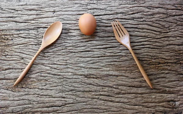 chicken egg with wood spoon on retro wood table background.the background has abstract surface pattern.