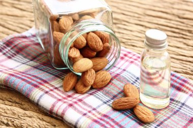 Ekoseli organik kahverengi badem tohumu ve şişesinde badem yağı olan kare şişede biraz badem..