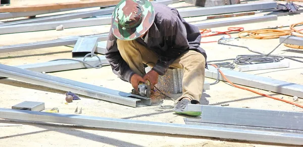 Açık hava şantiyesinde çalışan işçi. Elektrikli öğütücüyle metal kesme, parlayan kıvılcımlar