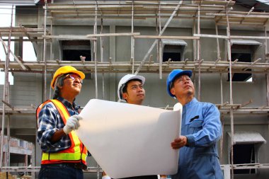 Proje denetiminin önünde duran bir grup mühendis binanın detaylarını inceliyor.