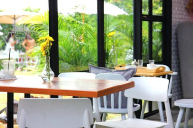 Kafe iç tasarımı. Beyaz sandalyeli cam vazoda sarı çiçekler.