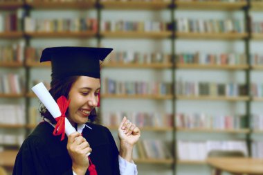 Bulanık kitap arkaplanı olan diplomalı mutlu mezun.