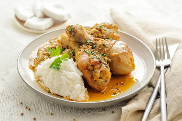 Chicken legs braised in curry and coconut sauce. With rice for garnish.