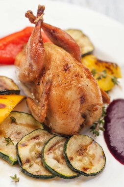 Izgara Kabak ve biber garnitür ve Berry sos ile ev yapımı pişmiş bıldırcın. Beyaz bir plakaya. Diyet için öğle ve akşam yemeği. Ketogenik diyet. Dikey görünüm.