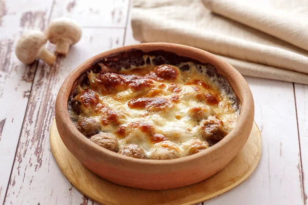 Baked mushrooms with cheese on earthenware. Hot vegetarian dish. Horizontal.