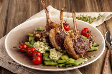 Yeşil fasulye ve kokulu tereyağı bir garnitür ile ızgara kuzu pirzola. Domates ve taze kekik ile. Ev yapımı pişmiş yemek. Ketojenik yiyecek. Tahta bir masa ve doğal bir peçete. Yatay görünümü kapatma. 