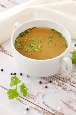 Baharat ve taze otlar ile pişmiş sıcak kemik suyu. Tıbbi diyet suyu ve süper gıda. Ketojenik diyet ve paleo diyet için. Ahşap bir arka plan üzerinde tek bir tabakta ve beyaz bir peçete ile hizmet.
