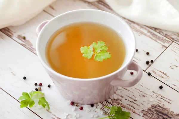 Baharat ve taze otlar ile pişmiş sıcak kemik suyu. Tıbbi diyet suyu ve süper gıda. Ketojenik diyet ve paleo diyet için. Ahşap bir arka plan üzerinde tek bir tabakta ve beyaz bir peçete ile hizmet.