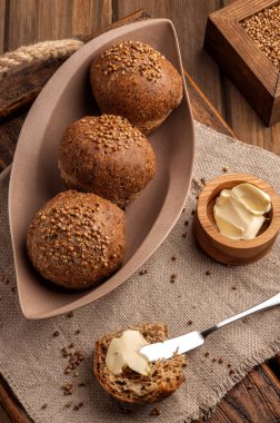 Kişniş tohumu ile pişirilen düşük karbonhidratlı glutensiz çörekler. Ahşap bir tepsi ve doğal rustik peçete üzerinde tereyağı ile servis edilir. Yukarı ve dikey görünüm. 