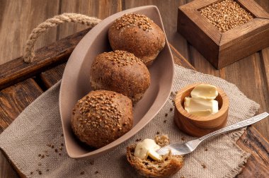 Kişniş tohumu ile pişirilen düşük karbonhidratlı glutensiz çörekler. Ahşap bir tepsi ve doğal rustik peçete üzerinde tereyağı ile servis edilir. Yukarı ve yatay görünüm. 