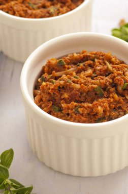 Kırmızı pesto sosu. Kurutulmuş domates, fındık ve taze otlar ile klasik Italyan sosu. Küçük beyaz bir kase hizmet. Yakın çekim ve dikey oryantasyon. 