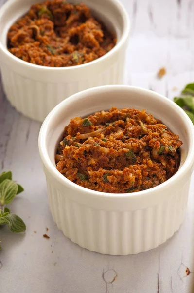 Kırmızı pesto sosu. Kurutulmuş domates, fındık ve taze otlar ile klasik Italyan sosu. Küçük beyaz bir kase hizmet. Yakın çekim ve dikey oryantasyon. 