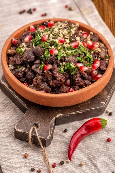 Tavuk Giblets kuchmachi geleneksel Gürcü çanak. Büyük bir kısmı rustik tarzda bir kil plaka üzerinde hizmet vermektedir. Nar tohumları ve yeşillikler ile servis edilir. Yakın çekim ve dikey görünüm. 