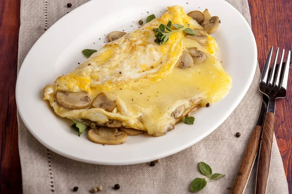 Mantar ve peynirle Fransız omlet. Büyük bir kısmı beyaz plaka üzerinde servis edilir.