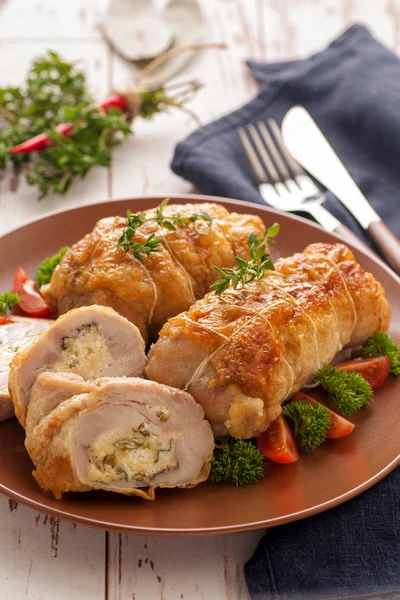 Stuffed chicken roll s vegetable garnish and herbs.