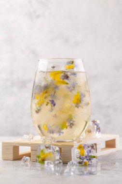 Açık gri arka planda buzlu ve çiçekli şampanya kokteyli. Hafif yaz içkisi. Yakın plan..