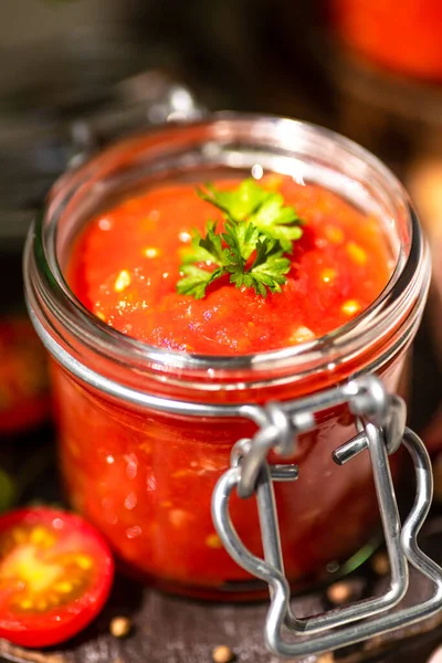 Tomato salsa in a glass jar. Homemade spicy tomato sauce with chilli, garlic and lime. Preparation of food for the winter. Ecological healthy food.