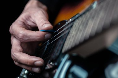 Gitarist elleri ve gitar telleri yakın. Elektro gitar çalan müzisyen. Seçici odak.