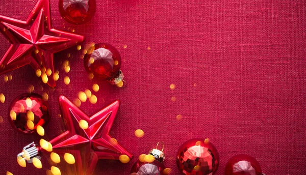 Red christmas decorations (stars and balls) on red canvas background