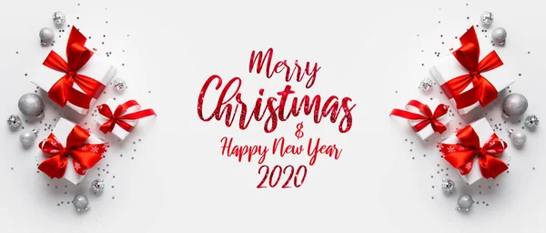 Merry Christmas and Happy Holidays greeting card, frame, banner. New Year. Noel. Christmas gifts and silver, red decor on white background top view. Winter xmas holiday theme. Flat lay