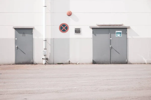 Backdoor to a storage hall with a no parking sign and an alarm nearby