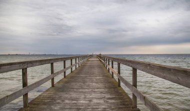 Bulutlu gri gökyüzü altında ahşap iskele perspektif görünümü