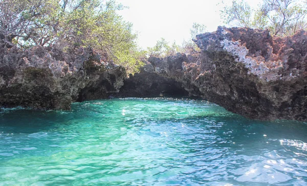 Mavi gökyüzünün altında büyük kayalar ile turkuaz okyanus koyun manzara görünümü