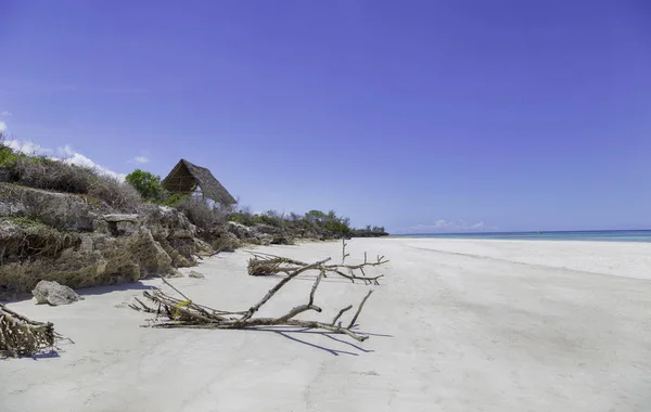 Mavi gökyüzü altında kayalık uçurum ile beyaz tropikal kumlu plaj