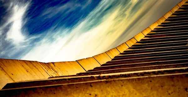 construction, the way to the sky, the way to succes, abstract yellow stairs and beautiful sky with white clouds, seems to be smeared with a brush