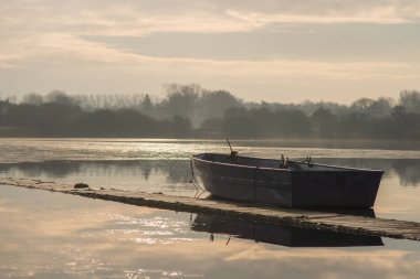 Yalnız bir insansız tekne boşta kalma donmuş bir gölün üzerinde Hornsea Mere sunrise sırasında oturur