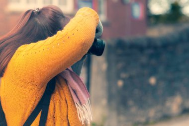Bir kış gününde bir hardal cableknit hırka giymiş bir fotoğrafta bir kadın fotoğrafçı