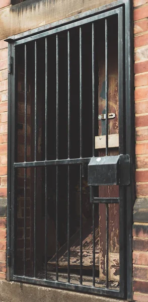 A smashed door behind a black metal gate — Stock Photo, Image