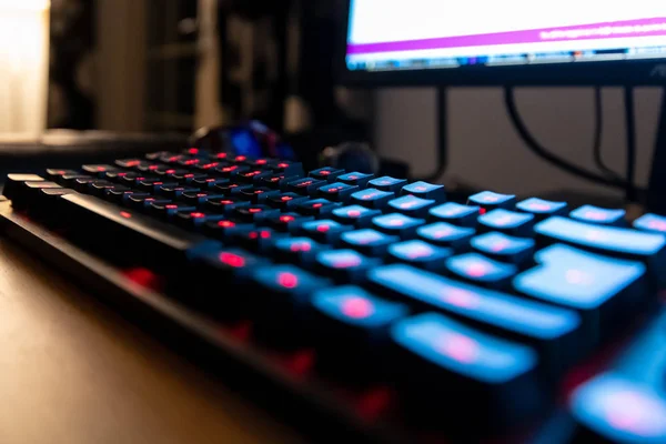 Kırmızı LED düğmeli siyah mekanik klavye, gece zamanında monitörün arka planını aydınlattı — Stok fotoğraf