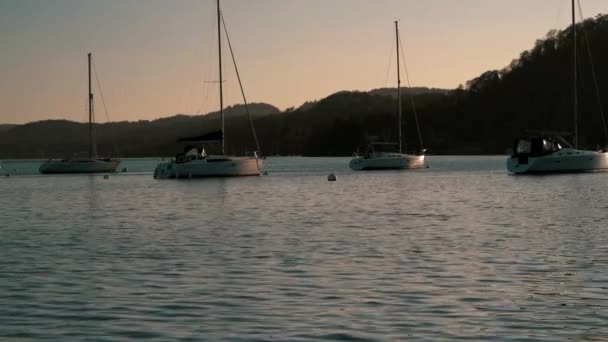 Парусные лодки сидят на спокойном озере Уиндермир на закате в Камбрии, Великобритания — стоковое видео