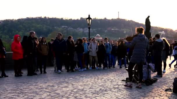 Прага, Чехія-10 квітня 2019: туристи слухають смугу гри на знаменитому мосту Чалес під час заходу сонця — стокове відео