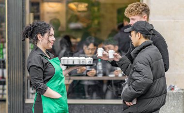 Prag, Çekya - 12 Nisan 2019: Bir kadın Starbucks çalışanı Prag eski şehir meydanında halka sıcak numuneler dağıtıyor