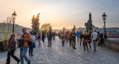 Turistler parlak bir gün batımı akşamı Başkent'te ünlü Charles Köprüsü çapraz