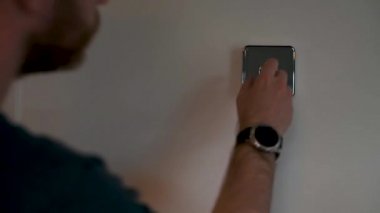 Sheffield, İngiltere - 29 Mayıs 2019: Mavi üstteki beyaz beyaz beyaz bir erkek hive termostatı ile etkileşime giriyor ve evin sıcaklığını değiştiriyor.