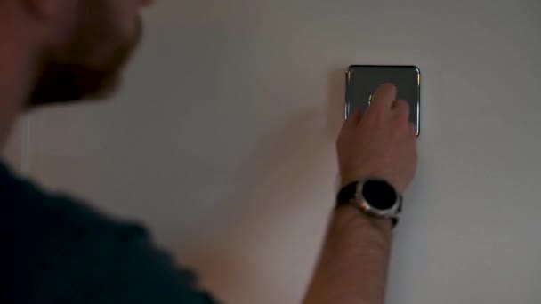 SHEFFIELD, Reino Unido - 29 DE MAIO DE 2019: Um homem branco caucasiano em um topo azul interage com um termostato de Colmeia e altera a temperatura da casa . — Vídeo de Stock
