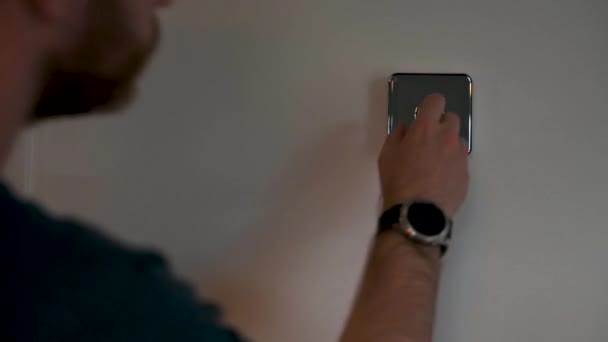 SHEFFIELD, UK - 29TH MAY 2019: A white caucasian male in a blue top interacts with a Hive thermostat and changes the temperature of the house. — Stock Video