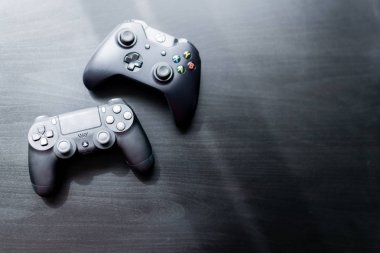 Xbox ve Playstation denetleyicisi koyu bir arkaplanda yan yana oturdular