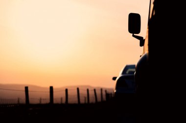 İki park edilmiş araba silueti Ingiltere 'de Peak District National Park pastel renkli günbatımı karşı oturmak