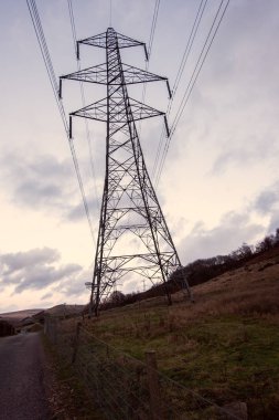Koyu büyük bir iletim kulesi, elektrik Pylon, sarı bir gün batımı karşı standları.