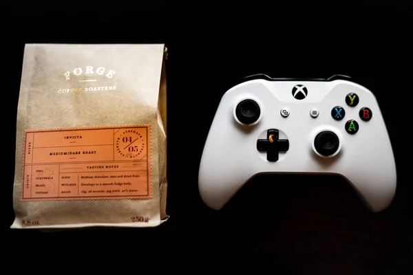 Xbox One game controller duduk di sebelah kantong kopi tanah dengan latar belakang hitam gelap — Stok Foto