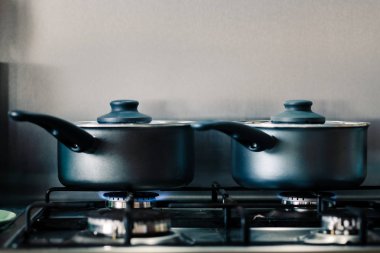 İçinde yiyecek pişirmek gibi buharda bir gaz Ocak üzerinde iki siyah parlak pişirme kapları