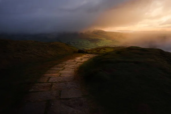 Nascer do sol épico sobre o Peak District National Park mostrando o único caminho através das colinas exuberantes — Fotografia de Stock