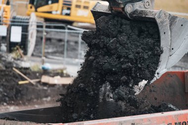 Bir kazıcı ve damperli kamyon temelleri için yer açmak için kir taşımak