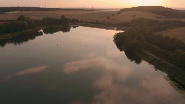 Wunderschöner Sonnenuntergang in der ländlichen englischen Landschaft mit epischen Ausblicken auf die Landschaft, während Bauern Weizenfelder ernten — Stockvideo