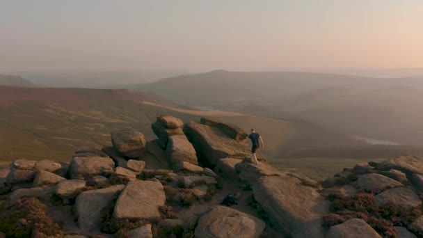 Aérienne - Suivre un jeune mâle grimpant le long d'une magnifique colline au coucher du soleil — Video